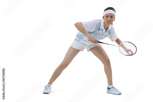 Young woman in sports wear playing badminton against white background