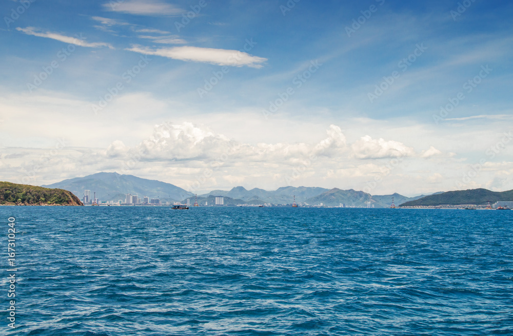 view of the coastline from the sea, urban buildings, mountains, against the blue sky and clouds, Nha Trang, Vietnam