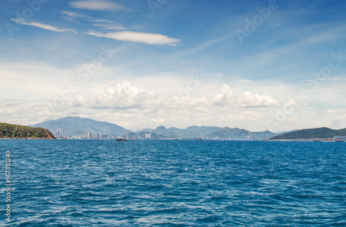 view of the coastline from the sea, urban buildings, mountains, against the blue sky and clouds, Nha Trang, Vietnam © Nemo67