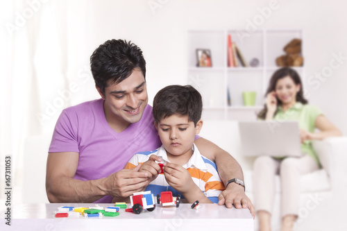 Father watching son play with toys