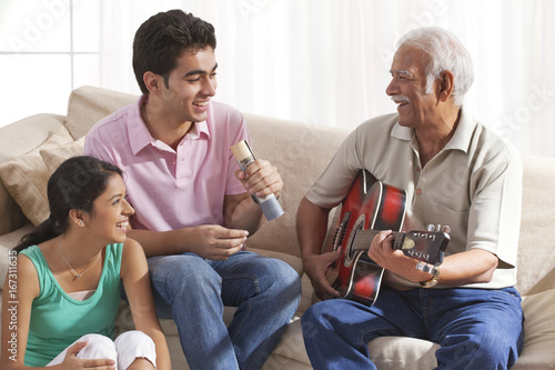 Grandfather playing the guitar and grandchildren singing © IndiaPix