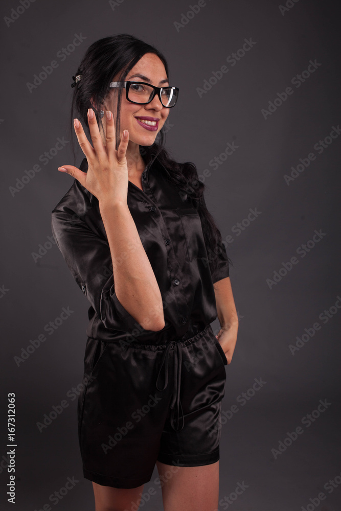 Young glad woman portrait of a confident businesswoman showing by hands on a black background. Ideal for banners, registration forms, presentation, landings, presenting concept. Young glad woman portrait of a confident businesswoman showing by hands on a black background. Ideal for banners, registration forms, presentation, landings, presenting concept.