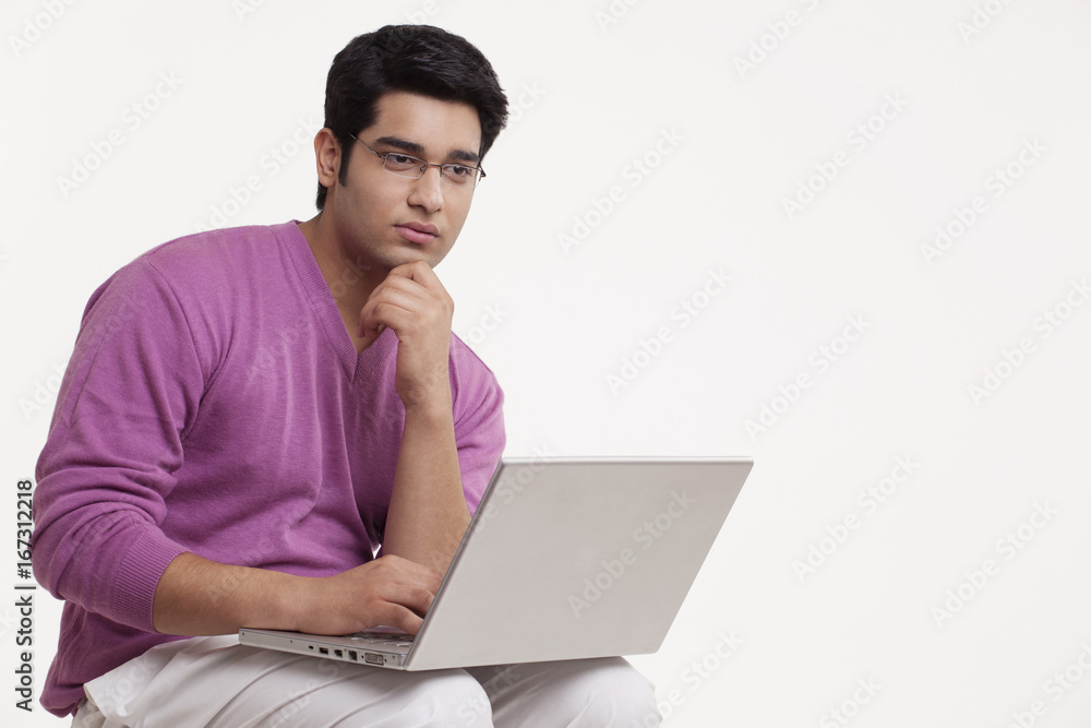 Young man thinking while using laptop Young man thinking while using laptop