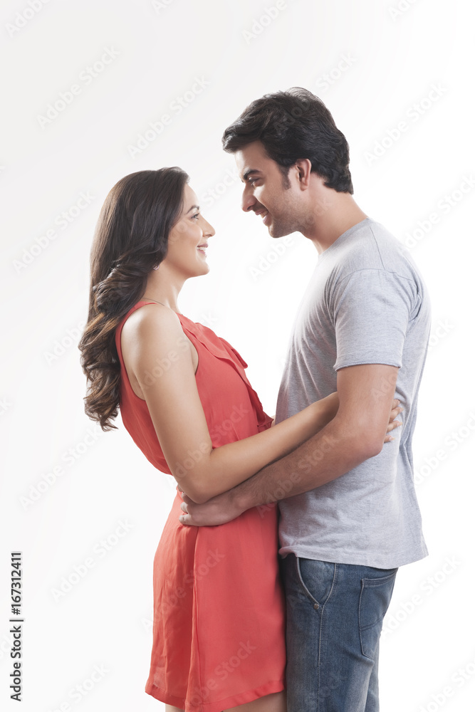 Profile shot of smiling couple embracing against white background Profile shot of smiling couple embracing against white background
