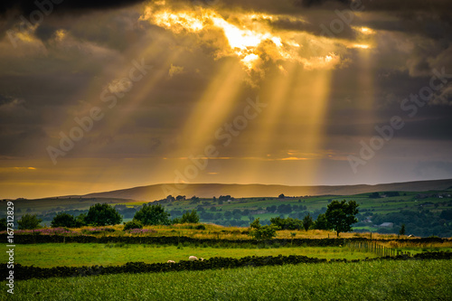 Summer sunset over landcape with sun rays through clouds