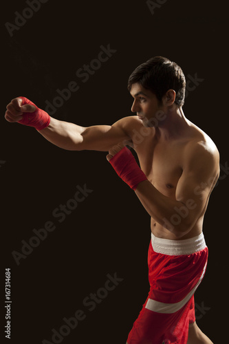 Side view of young male boxer punching isolated over black background © IndiaPix