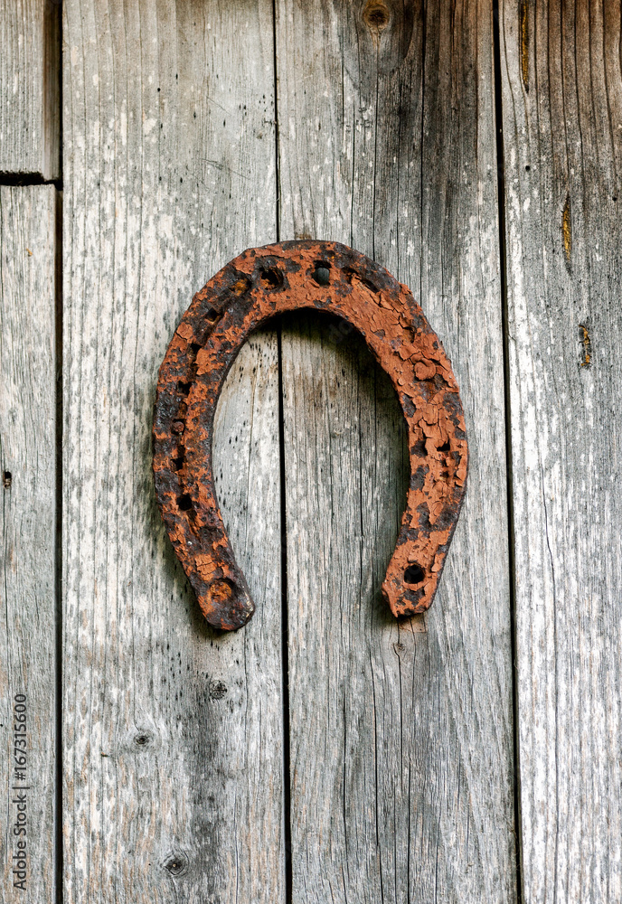 Old metal rusted horseshoe hanged on gray wooden wall, vertical Old metal rusted horseshoe hanged on gray wooden wall, vertical