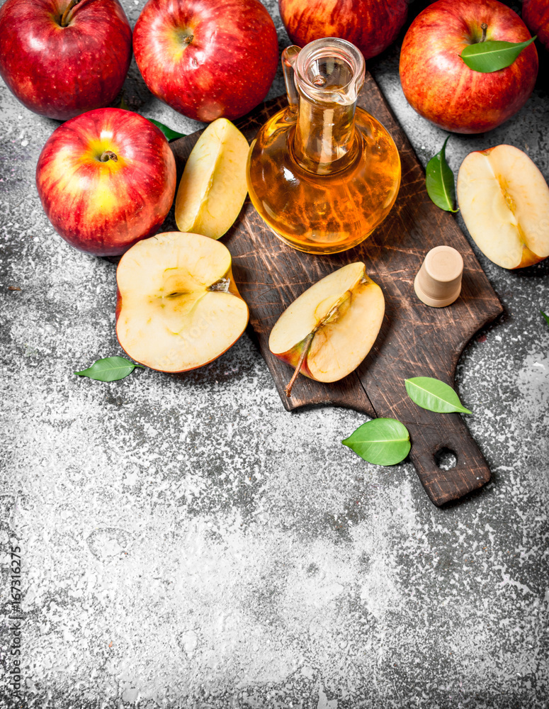 Apple cider vinegar with fresh apples on cutting Board.