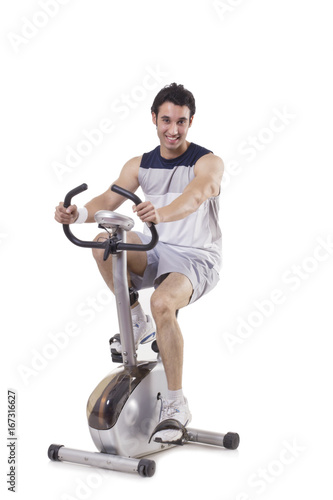 Portrait of a young fit man on exercise bike over white background 