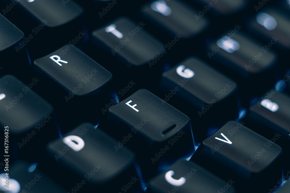 Macro photo of mechanical keyboard. Focus on the letter R and F keys. The letters are etched on black plastic keycaps to reveal the led backlight. Other keys are out of focus in the background. Macro photo of mechanical keyboard. Focus on the letter R and F keys. The letters are etched on black plastic keycaps to reveal the led backlight. Other keys are out of focus in the background.