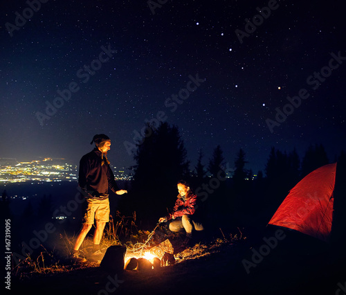 Romantic couple near campfire at starry night