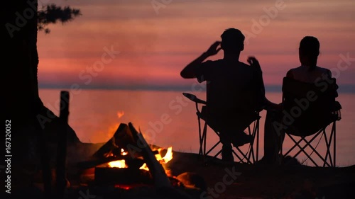 Couple is Sitting near Campfire at Night.