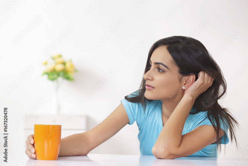 Thoughtful woman with coffee cup at home