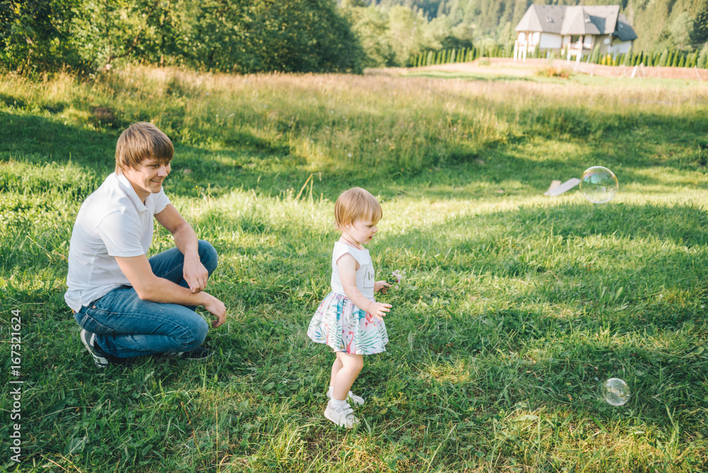 Fototapeta premium father plays with his daughter with soapbubble