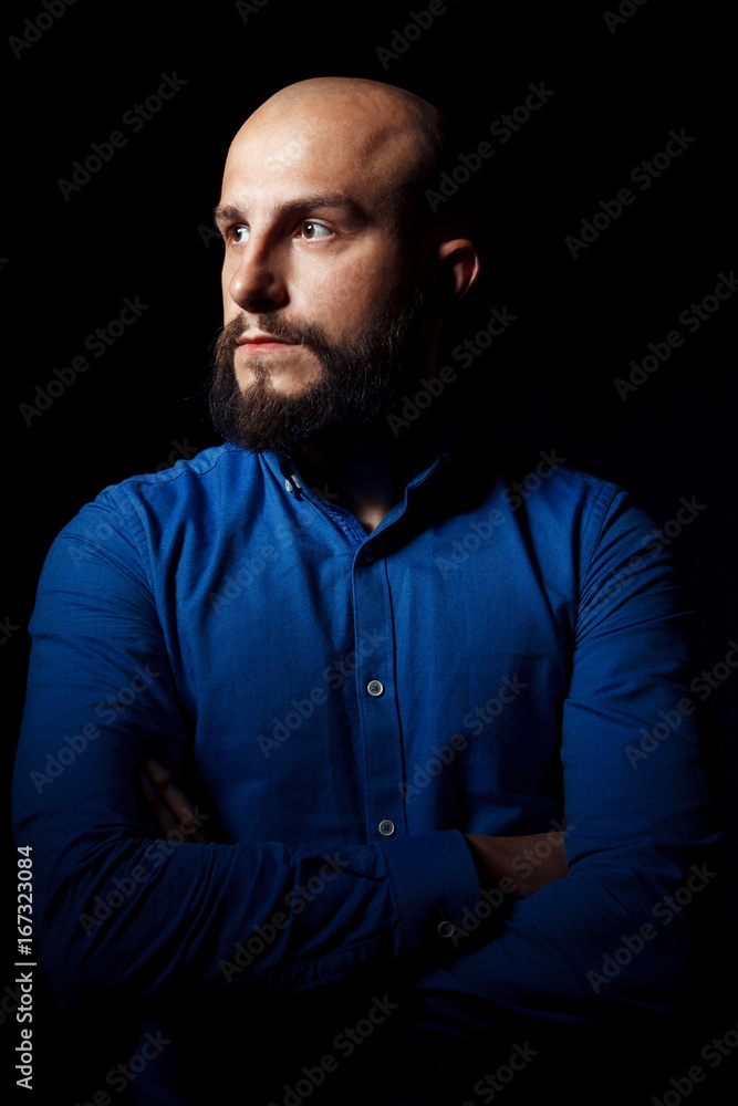 Portrait of a successful businessman on black background. Handsome bold man with beard