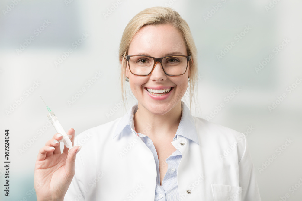 Junge hübsche lächelnde Ärztin mit Spritze vor Labor verschwommen im Hintergrund Junge hübsche lächelnde Ärztin mit Spritze vor Labor verschwommen im Hintergrund