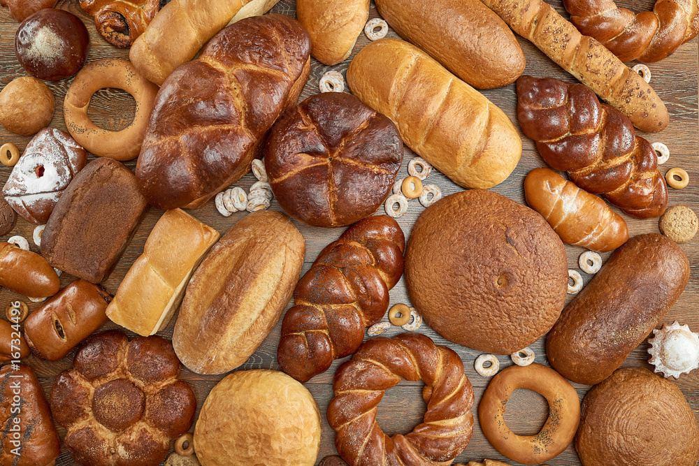 Top view shot of a wooden table full of different kinds of delicious freshly baked organic bread copyspace layout food nutrition healthy concept. 