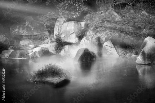 Beautiful Korean Yongsan park Garden, stones trees and lake with small fog and sun beam. black and white photo