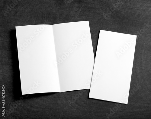 blank white folding paper flyer on a black chalkboard