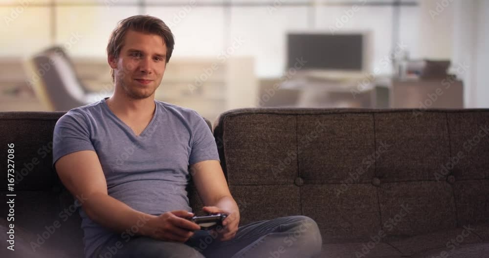 Young man on couch playing on a console Young man on couch playing on a console