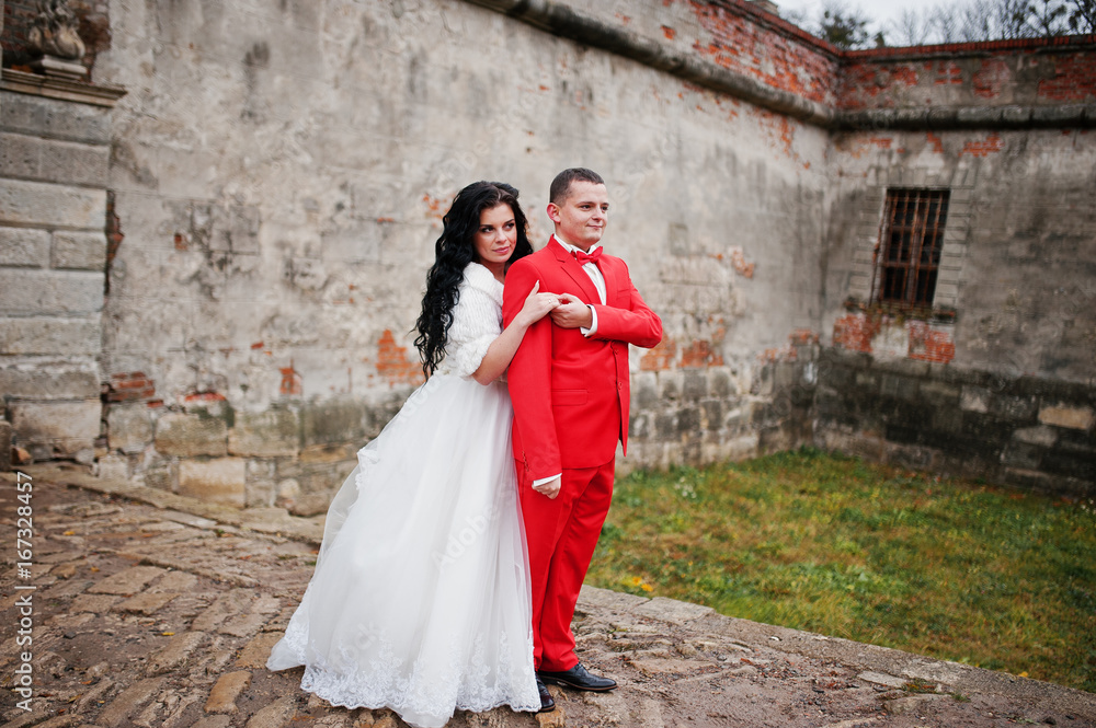 Beautiful wedding couple posing in the yard of an old castle with ancient walls.