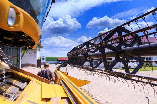 The mechanics repair the yellow Combine harvester in the farm yard. Concept theme repair, mechanics, production, industry, agribusiness, production of food, agricultural production. Not staged photo. photo