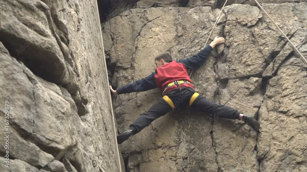 Young man rock climbing on a big natural rock Young man rock climbing on a big natural rock