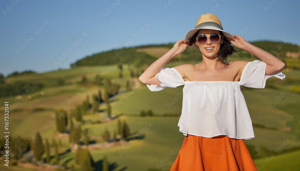 Tuscany tourism - woman in red dress visits Tuscan countryside in Siena province, Italy.