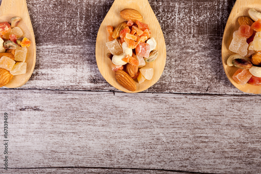 Fototapeta premium Healthy different type of nuts and sweet in wooden spoon on wooden background in studio photo