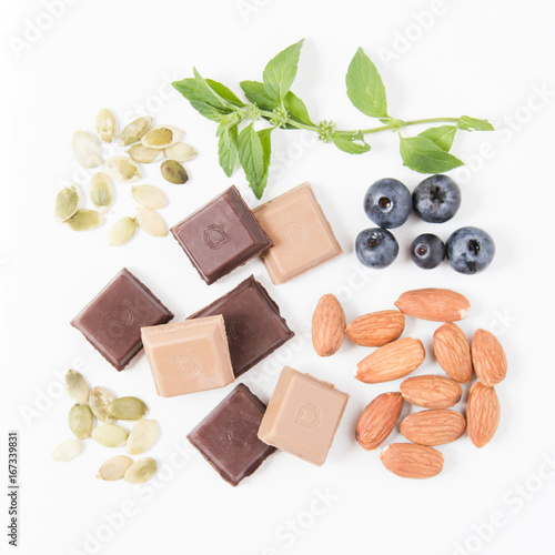 Healthy vegan snacks: pumpkin seeds, vegan raw chocolate, almonds, blueberries and mint leaves. Vegan lifestyle. Natural sweets. Healthy diet. Top view ingredients