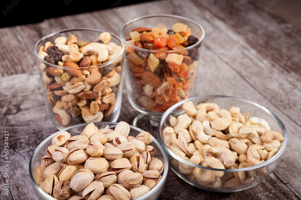 Healthy mix of dried nuts and sweets in was glass on wooden background in studio photo