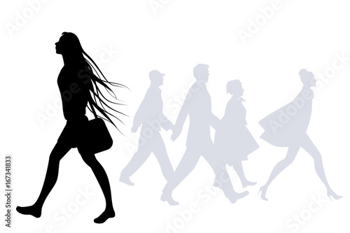 Teen girl with long hair in the wind walking on the street. Silhouettes of people in the background
