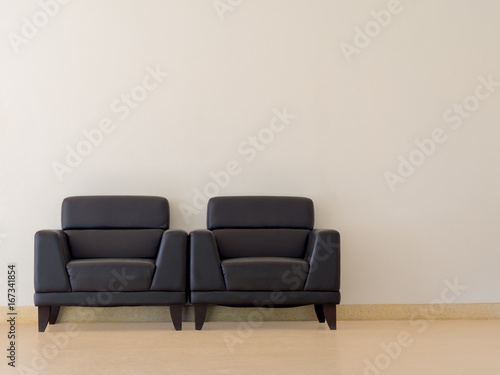 The black sofa is located in the room. There is a white concrete wall. © neramit