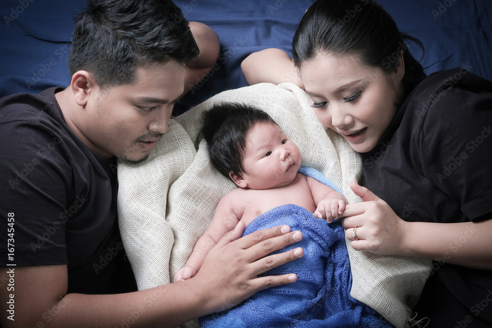 family portrait of young asian mum and dad and boy newborn in black background . family portrait of young asian mum and dad and boy newborn in black background .
