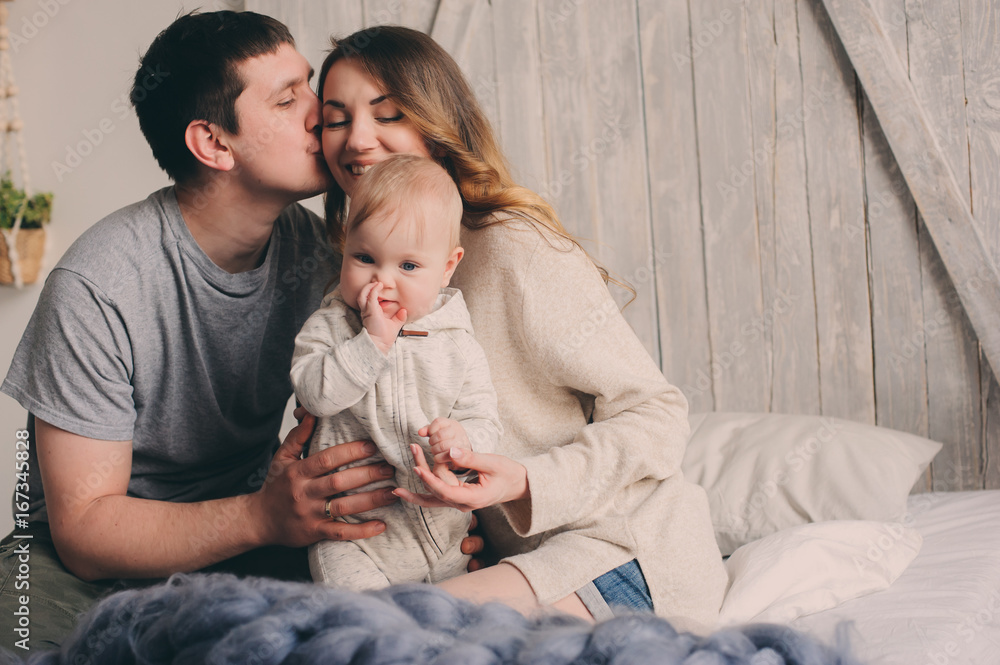 happy family playing at home on the bed. Lifestyle capture of mother, father and baby in modern scandinavian interior