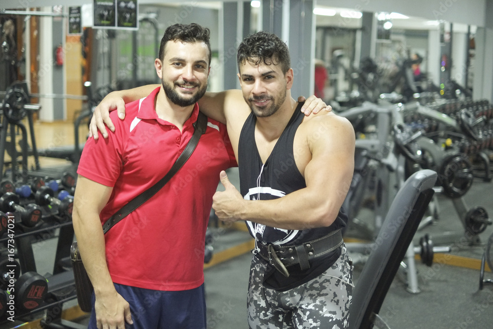 Brothers training in gym lifting weights, posing after training