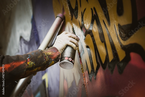 Graffiti artist painting with aerosol spray on the wall