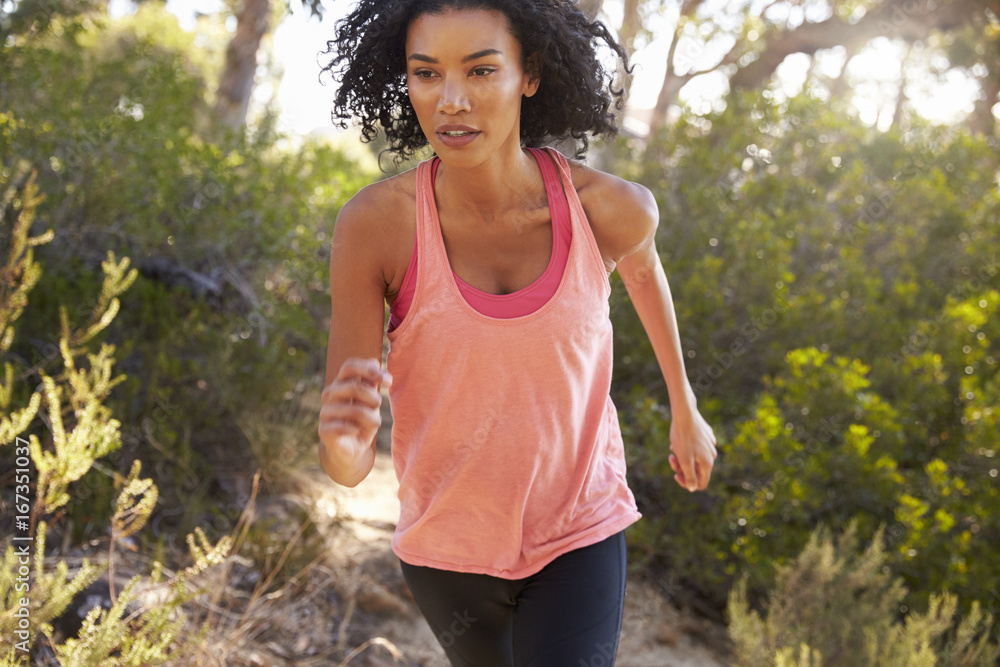 Determined young black woman jogging in a forest, close up Determined young black woman jogging in a forest, close up