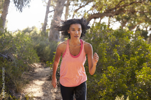 Fototapeta Naklejka Na Ścianę i Meble -  Young black woman jogging in a forest, close up
