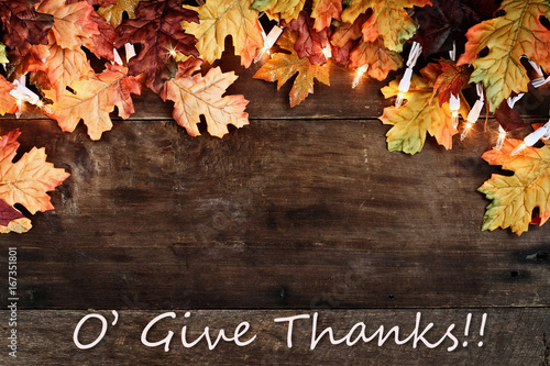 Fall Leaves Lights and Give Thanks Text over Wooden Background