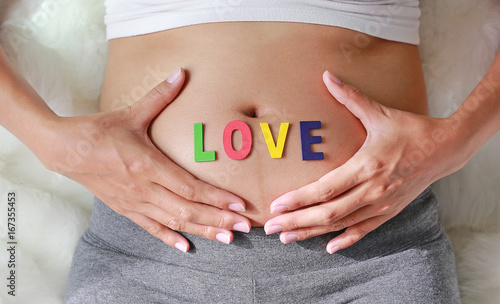 Wallpaper Mural Close up Pregnant woman sitting on soft sofa and touching her belly with sign LOVE in front of her belly. Torontodigital.ca