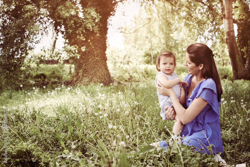 Fototapeta premium Pregnant mother playing with little daughter in park. Mother and daughter in nature.