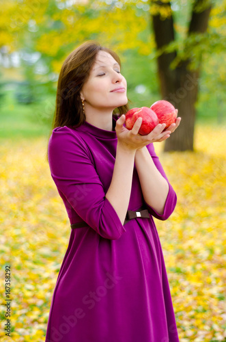Young beautiful pregnant girl with apples in the fall