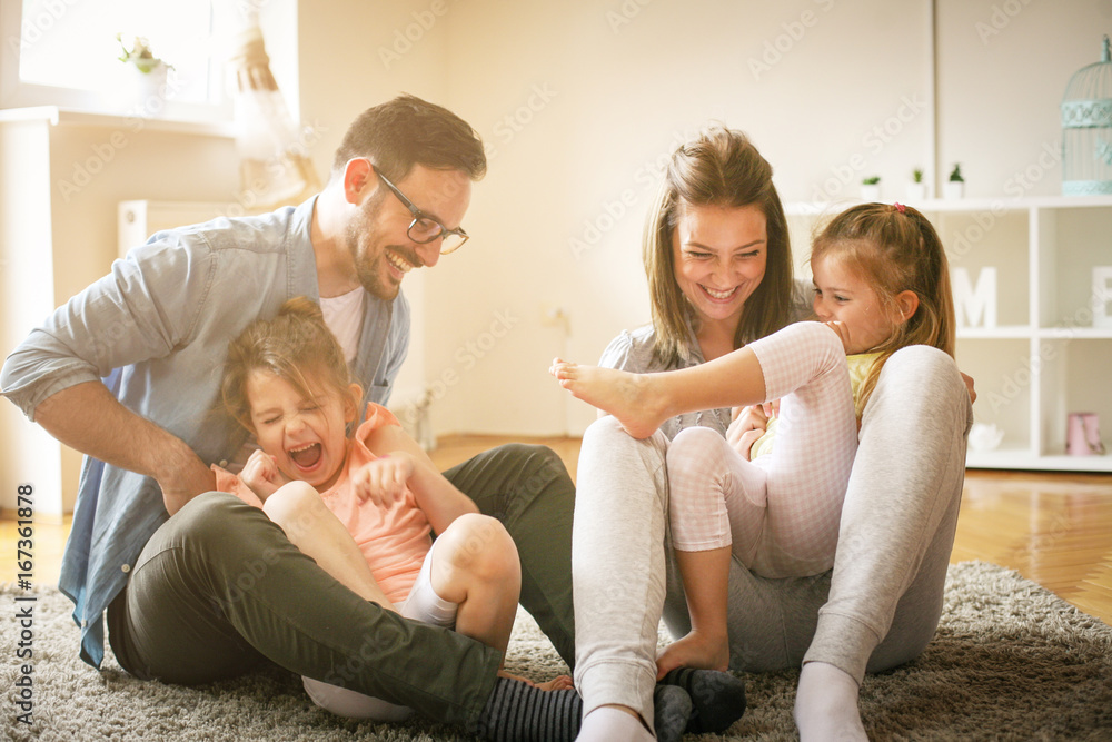 Happy family with two daughters playing at home. Family sitting on floor and playing together. Happy family with two daughters playing at home. Family sitting on floor and playing together.