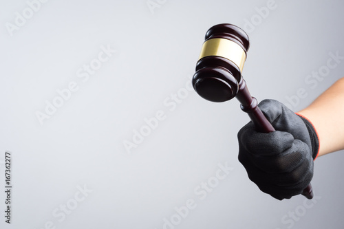 Hand holding wooden judge's gavel as a illegal or injustice sign