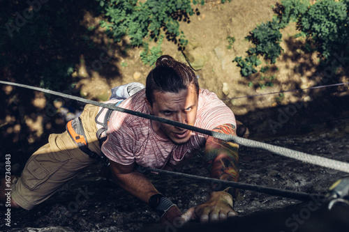 Concentrated Man Climber Climbs A Steep Cliff. Extreme Lifestyle Outdoor Activity Concept