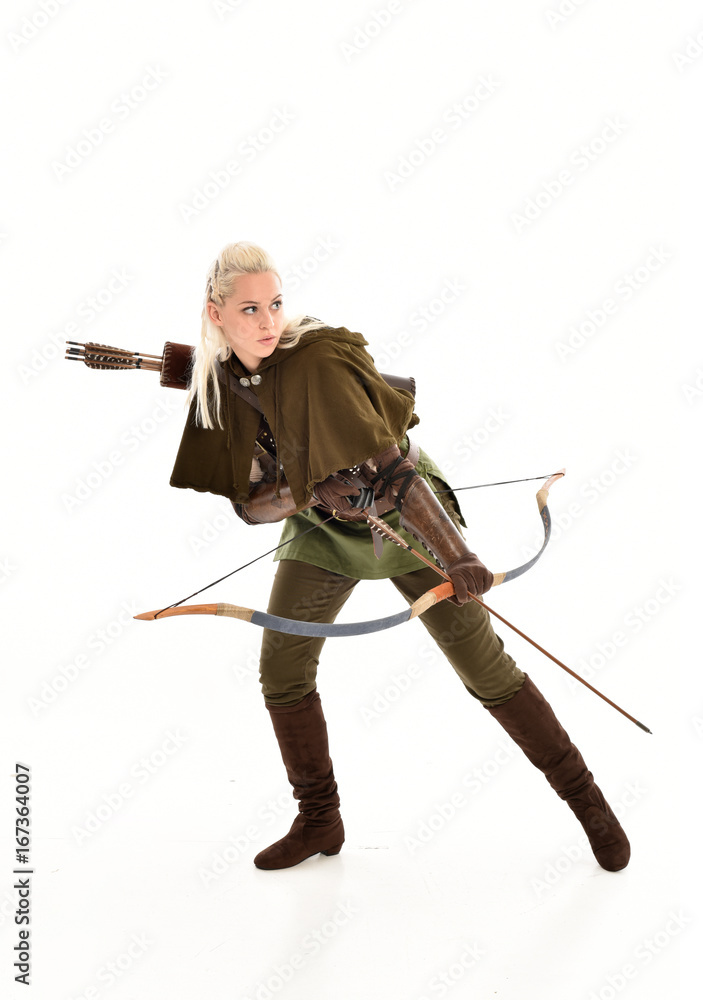 full length portrait of a blonde girl wearing green and brown medieval costume, holding a bow and arrow. isolated on white background. full length portrait of a blonde girl wearing green and brown medieval costume, holding a bow and arrow. isolated on white background.