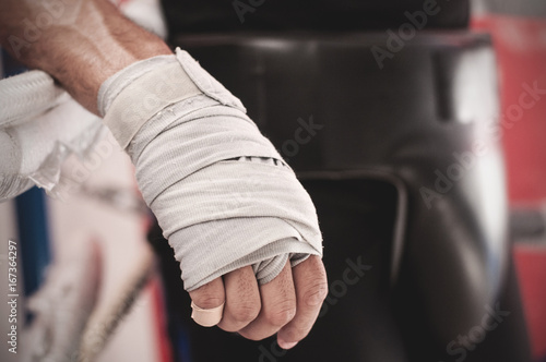 Fototapeta Naklejka Na Ścianę i Meble -  Close up of hand of boxer leaning on ropes on a boxing ring.