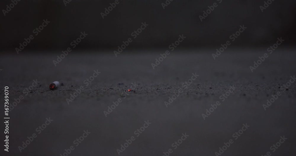Close up, lit cigarette falls on pavement Close up, lit cigarette falls on pavement