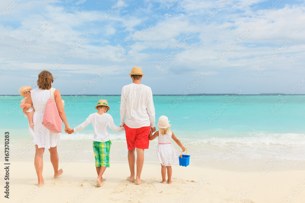 happy family with three kids walk on beach